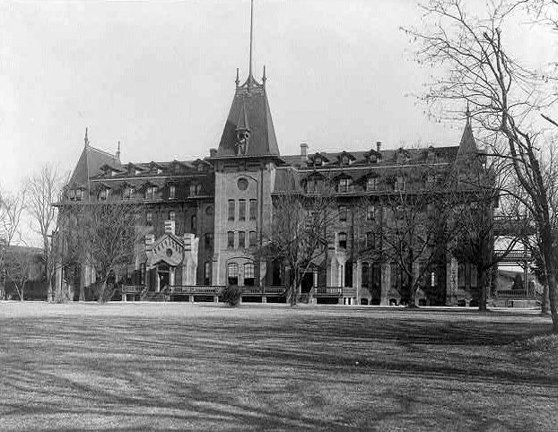 Virginia Hall, a large Victorian building with a central tower and dormer windows, behind a lawn and bare trees